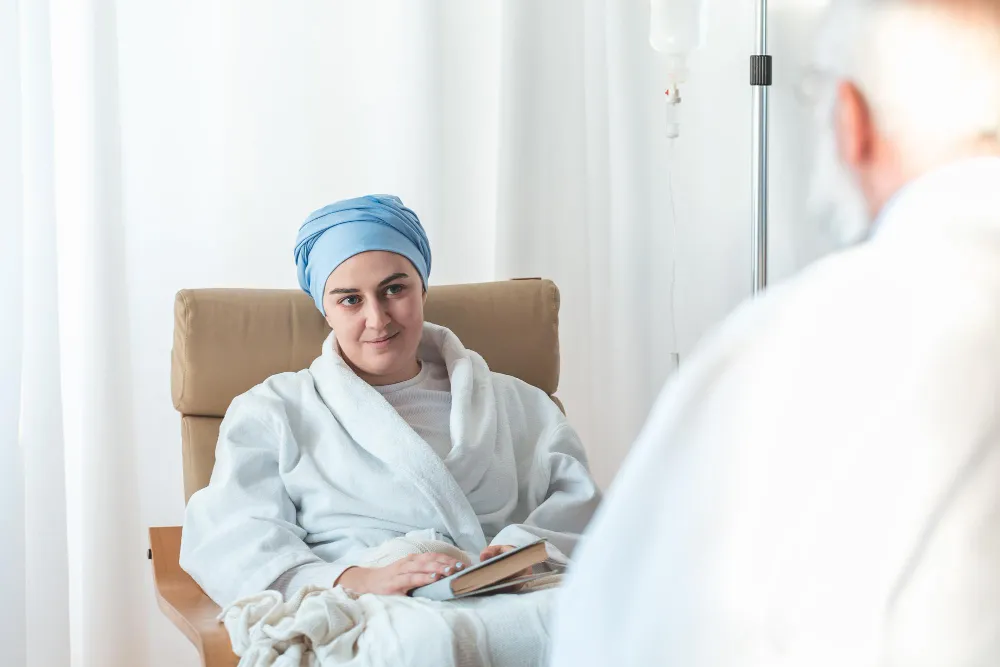 Mulher com turbante azul e roupão branco, lendo livro, em busca de BPC LOAS para pessoa com câncer.