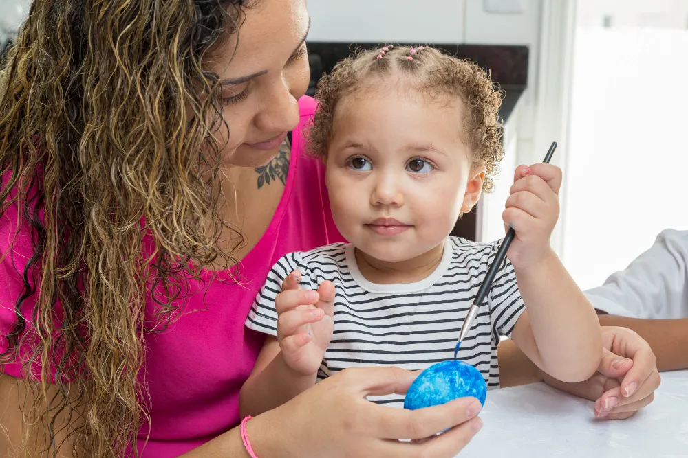 Mãe e filho autista pintando ovo, buscando BPC LOAS.